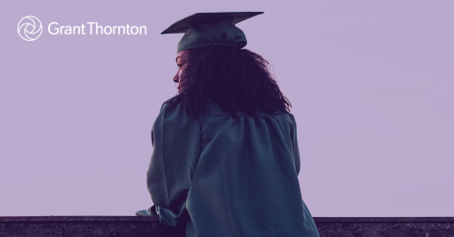 Woman in a graduation gown looking over a building