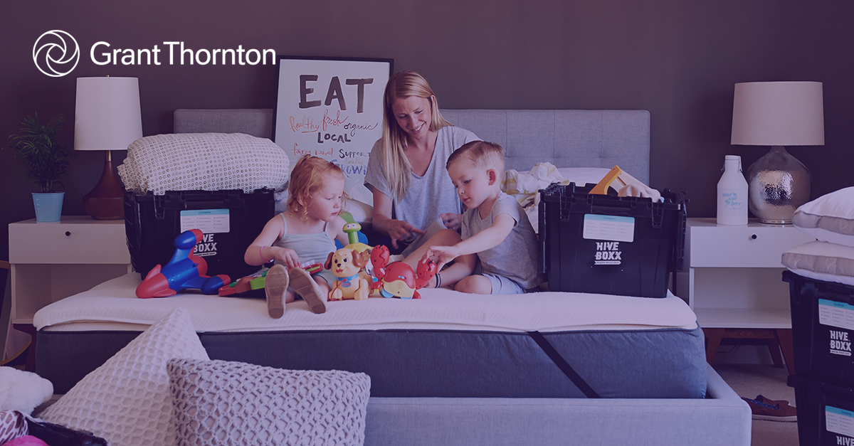 Woman sitting on bed two children and moving boxes