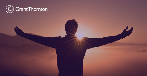 Man with open arms facing sunrise