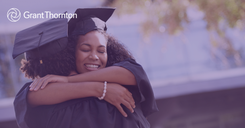 Two women in graduation gowns hugging